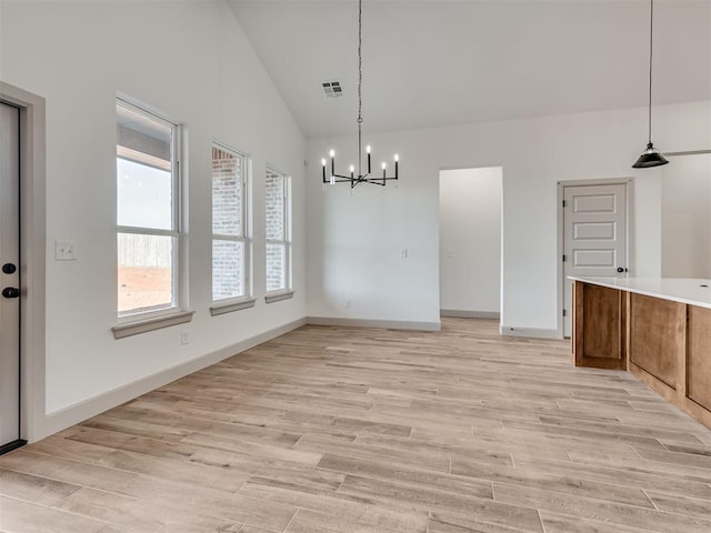 unfurnished dining area featuring a chandelier, high vaulted ceiling, visible vents, baseboards, and light wood-style floors