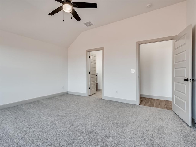 unfurnished bedroom featuring lofted ceiling, light colored carpet, a ceiling fan, baseboards, and visible vents