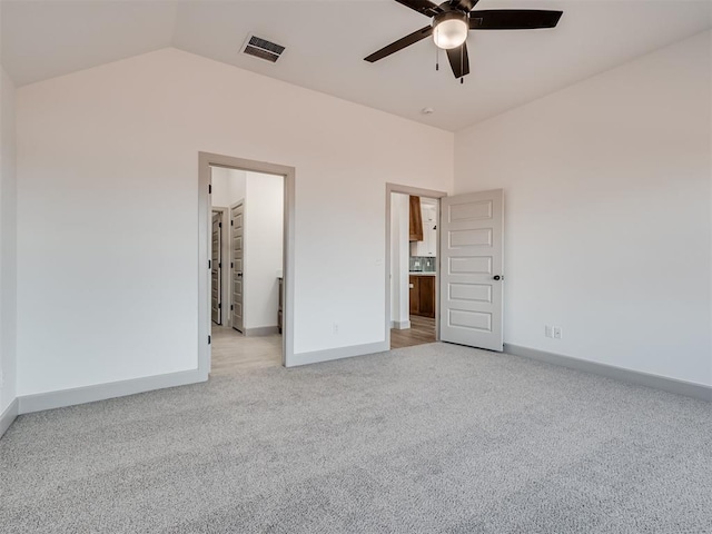 unfurnished bedroom with lofted ceiling, baseboards, visible vents, and light colored carpet