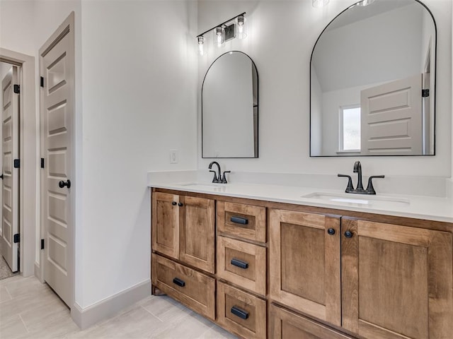 bathroom with a sink, baseboards, and double vanity