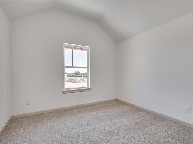 carpeted empty room with baseboards and vaulted ceiling