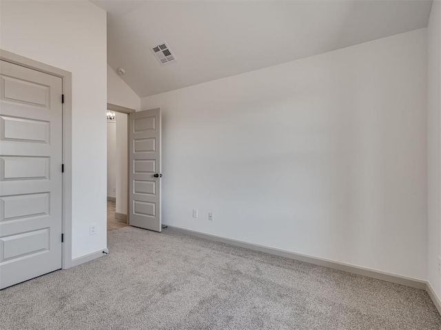 carpeted empty room featuring lofted ceiling, visible vents, and baseboards