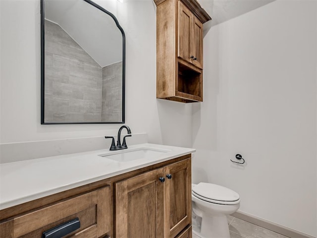 bathroom with toilet, lofted ceiling, and vanity