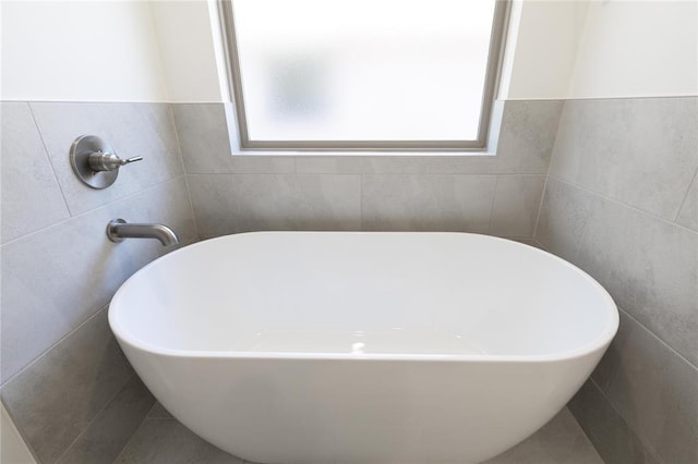 full bathroom with a freestanding bath and tile walls
