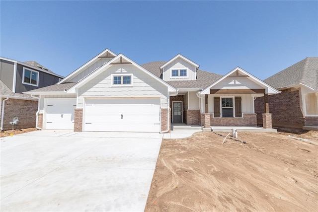 craftsman house with a shingled roof, a garage, concrete driveway, and brick siding