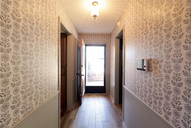 corridor with hardwood / wood-style floors and a textured ceiling