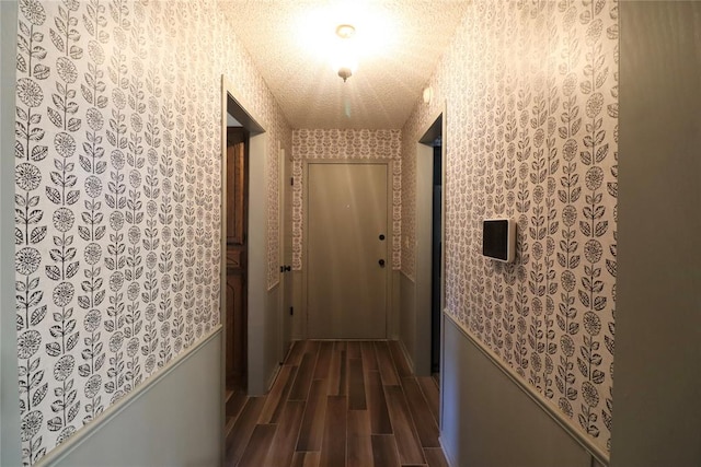 corridor with a textured ceiling and dark wood-type flooring