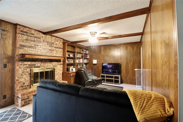 carpeted living room with beam ceiling, ceiling fan, wood walls, a textured ceiling, and a fireplace