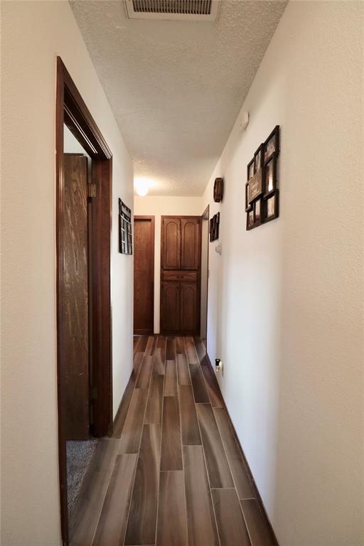 corridor with a textured ceiling and dark hardwood / wood-style floors