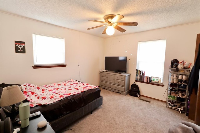 carpeted bedroom with ceiling fan and a textured ceiling