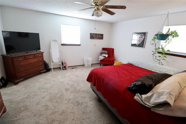 bedroom with light carpet, a textured ceiling, multiple windows, and ceiling fan