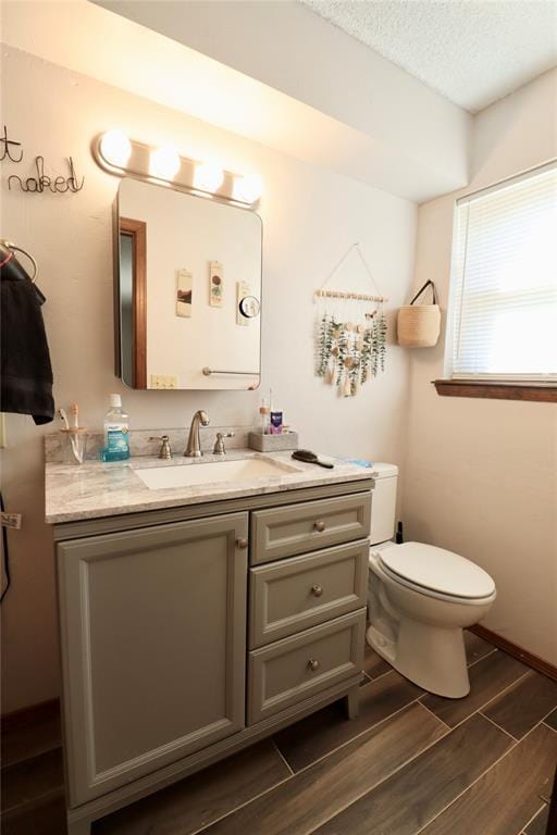 bathroom with hardwood / wood-style flooring, vanity, toilet, and a textured ceiling