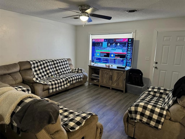 living room with a textured ceiling, ceiling fan, and dark hardwood / wood-style floors