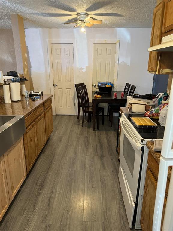 kitchen with ceiling fan, dark hardwood / wood-style flooring, a textured ceiling, and white electric range