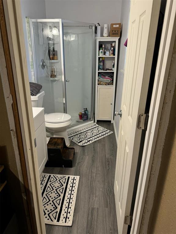 bathroom featuring vanity, wood-type flooring, an enclosed shower, and toilet