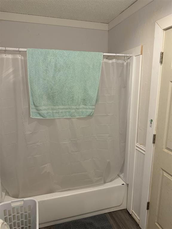 bathroom featuring hardwood / wood-style floors, shower / bathtub combination with curtain, and a textured ceiling