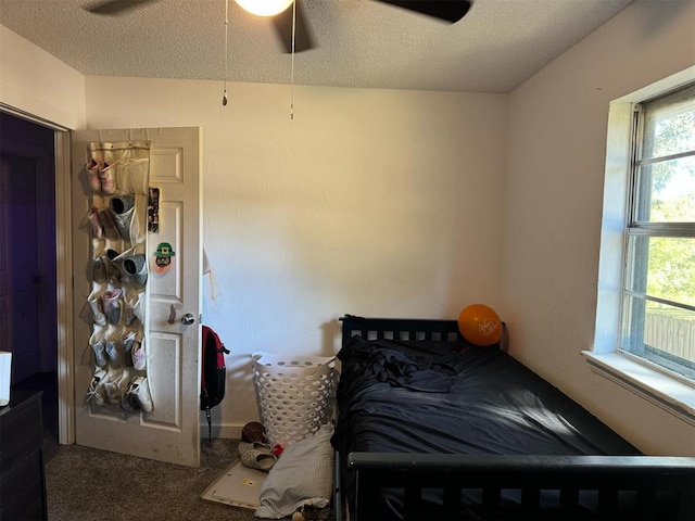 carpeted bedroom featuring ceiling fan and a textured ceiling