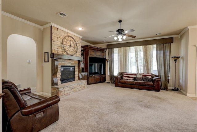 carpeted living room featuring ceiling fan, a stone fireplace, and crown molding