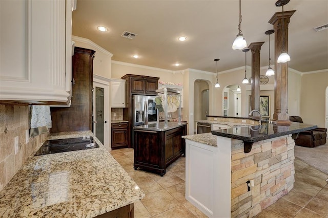 kitchen featuring a spacious island, sink, tasteful backsplash, decorative light fixtures, and dark brown cabinets