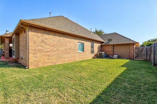 rear view of house with a yard, cooling unit, and a garage