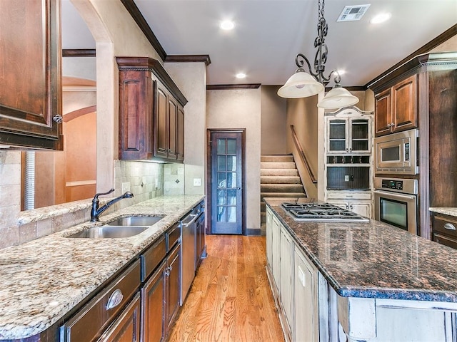 kitchen with sink, a center island, dark stone counters, and appliances with stainless steel finishes