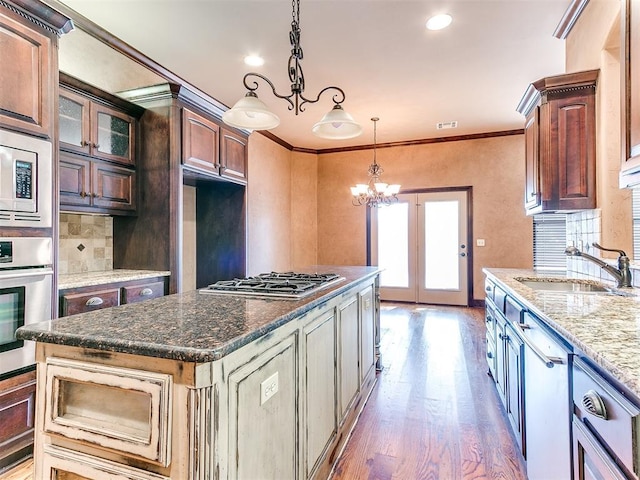 kitchen with ornamental molding, dark brown cabinetry, stainless steel appliances, sink, and a center island