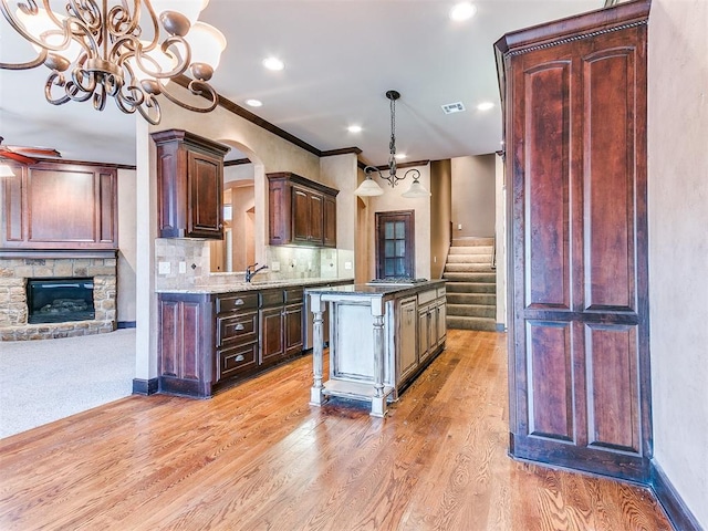 kitchen with a center island, hanging light fixtures, tasteful backsplash, light stone counters, and a fireplace