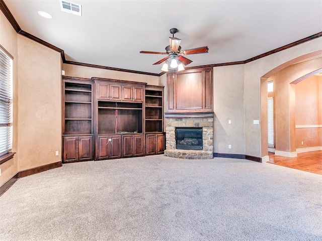 unfurnished living room with ceiling fan, a fireplace, light carpet, and ornamental molding