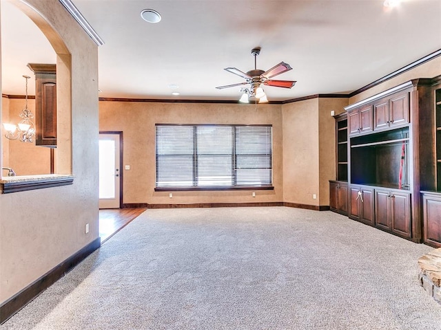 unfurnished living room with ceiling fan with notable chandelier and crown molding