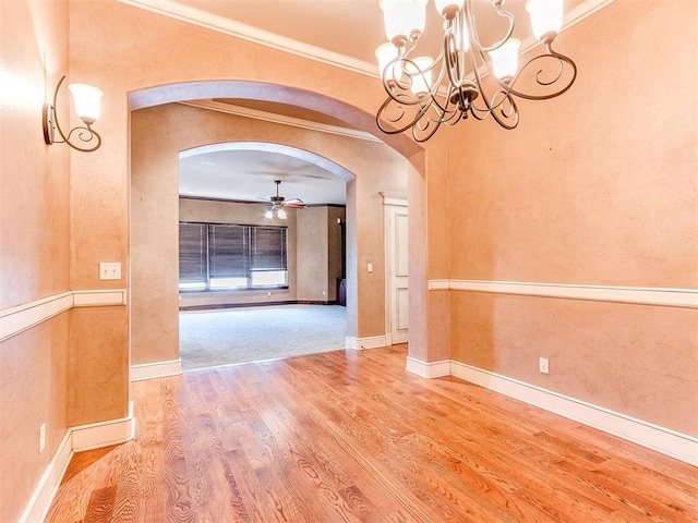 unfurnished dining area with hardwood / wood-style floors, ceiling fan with notable chandelier, and ornamental molding