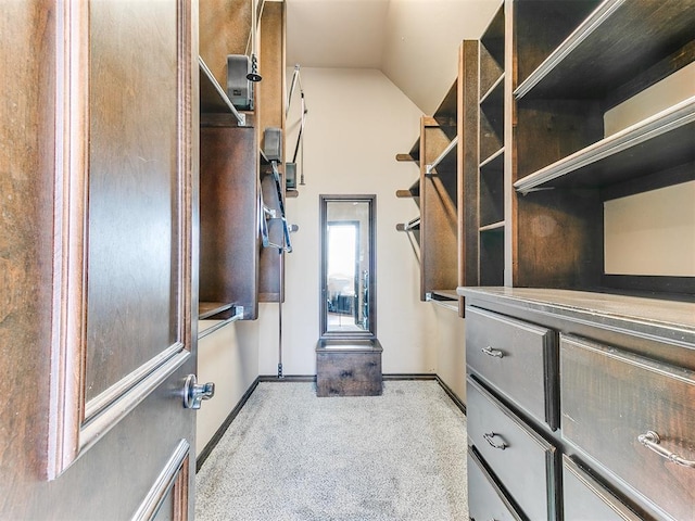 spacious closet featuring light colored carpet and lofted ceiling