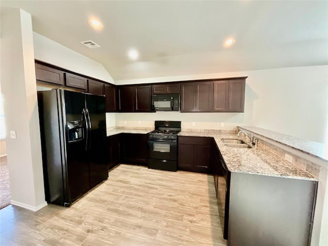 kitchen with black appliances, sink, light hardwood / wood-style flooring, light stone countertops, and kitchen peninsula