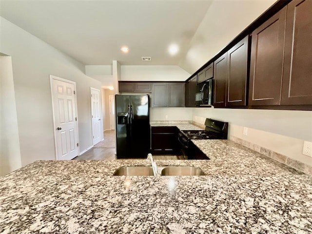 kitchen featuring light stone counters, sink, black appliances, and dark brown cabinets