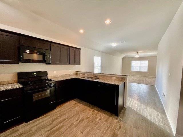 kitchen with black appliances, light stone countertops, kitchen peninsula, and light hardwood / wood-style flooring