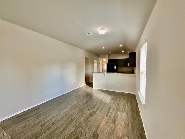 unfurnished living room featuring plenty of natural light and dark hardwood / wood-style floors