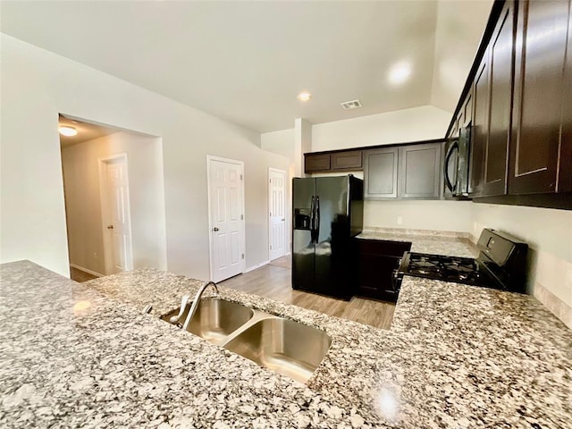 kitchen featuring kitchen peninsula, light wood-type flooring, dark brown cabinets, sink, and black appliances