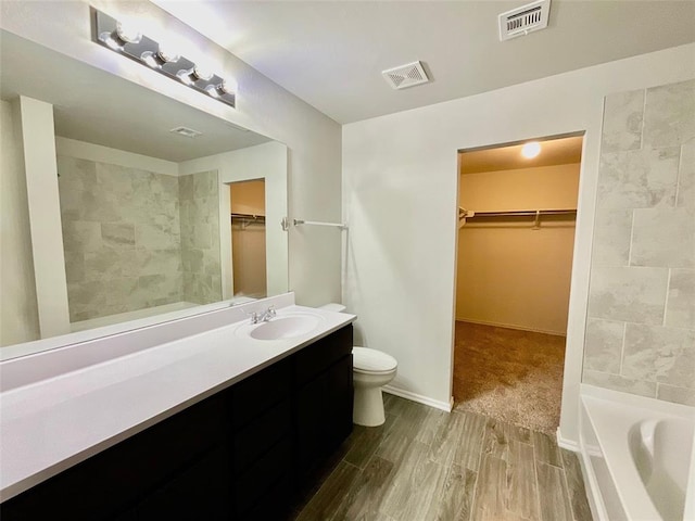 bathroom featuring a tub to relax in, vanity, wood-type flooring, and toilet