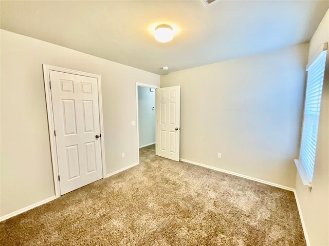 unfurnished bedroom featuring light colored carpet and a closet