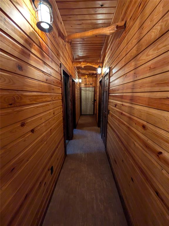 hallway with beam ceiling, dark hardwood / wood-style flooring, wooden ceiling, and wood walls