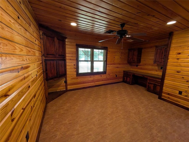 interior space featuring wood ceiling, ceiling fan, built in desk, and wooden walls