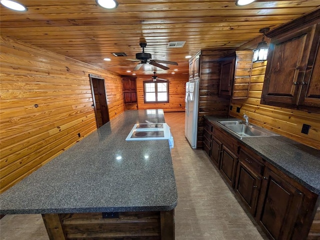 kitchen featuring wooden ceiling, wooden walls, and sink