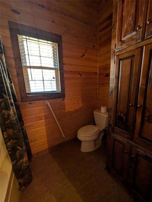 bathroom with wood walls and toilet