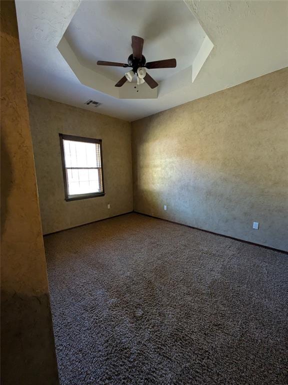 unfurnished room featuring carpet, ceiling fan, and a raised ceiling