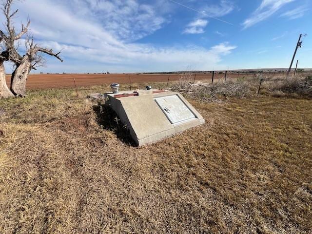 entry to storm shelter featuring a rural view