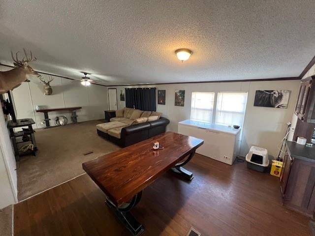 living room featuring ornamental molding, a textured ceiling, ceiling fan, and dark wood-type flooring