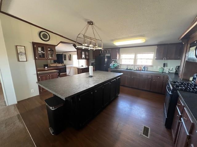 kitchen with dark hardwood / wood-style flooring, a center island, hanging light fixtures, and black appliances