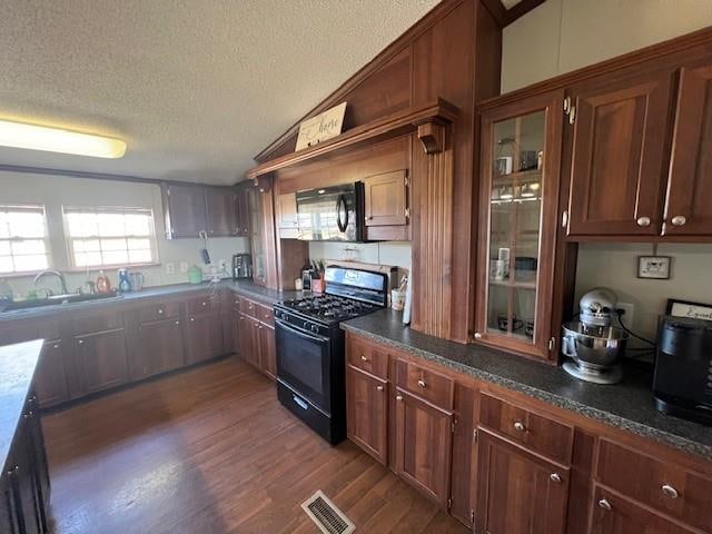 kitchen featuring dark hardwood / wood-style flooring, a textured ceiling, sink, black appliances, and dark stone countertops