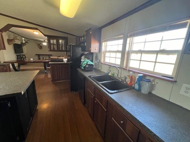 kitchen featuring lofted ceiling, black appliances, sink, dark hardwood / wood-style flooring, and dark brown cabinetry