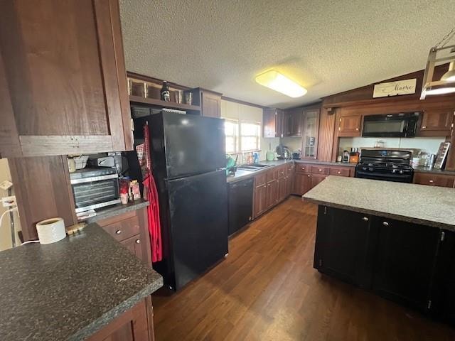 kitchen featuring dark hardwood / wood-style flooring, a textured ceiling, black appliances, a kitchen island, and lofted ceiling