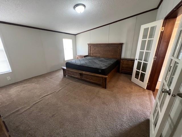 unfurnished bedroom featuring carpet, french doors, a textured ceiling, and ornamental molding